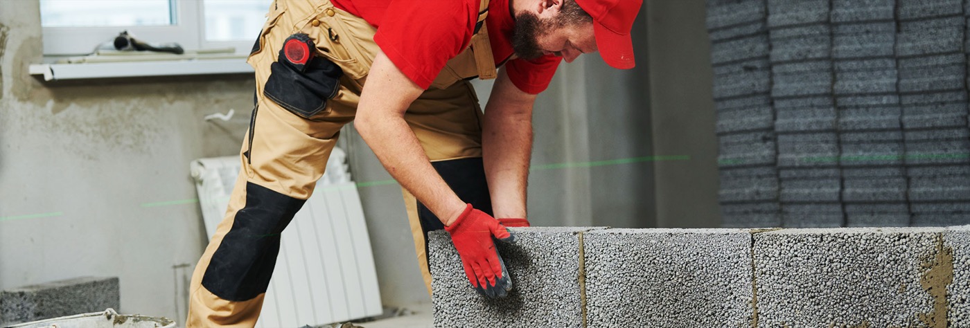 Maurer der Salioski Bau GmbH setzt mit Laser-Nivellierung eine Mauerwerkswand aus Leichtbetonsteinen